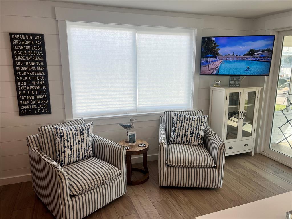 Two striped armchairs sit before a window with a television mounted on the wall — 6020 MIDNIGHT PASS ROAD UNIT 54, SARASOTA, FL