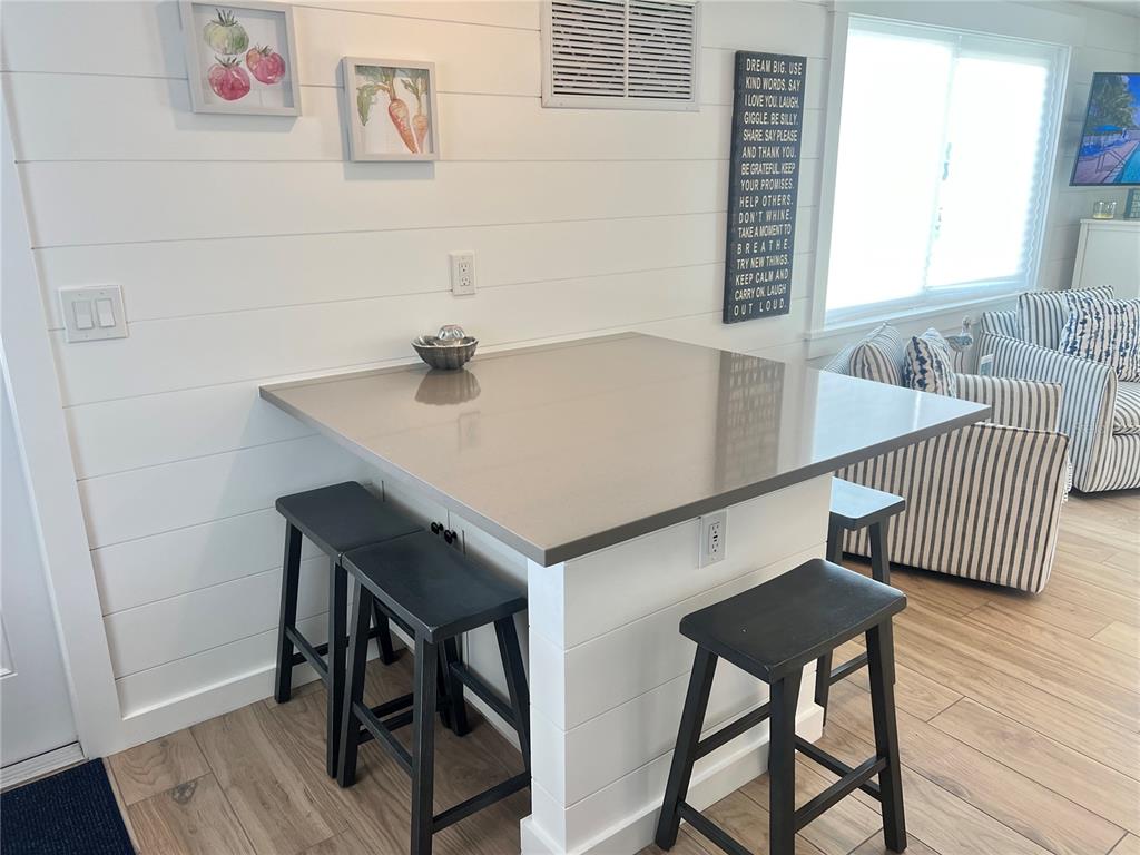 A kitchen island with a gray countertop and black stools sits against a shiplap wall — 6020 MIDNIGHT PASS ROAD UNIT 54, SARASOTA, FL