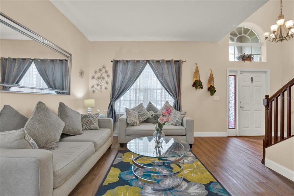 A living room features light-colored sofas, a glass coffee table, and a patterned area rug — 31405 GLENDALOUGH WAY, WESLEY CHAPEL, FL