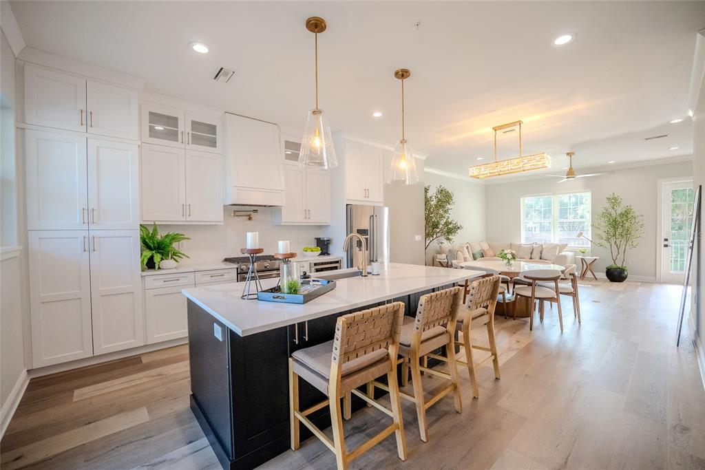 A kitchen with a dark island and white cabinets opens into a living and dining area — 141 SE WATULA AVENUE, OCALA, FL