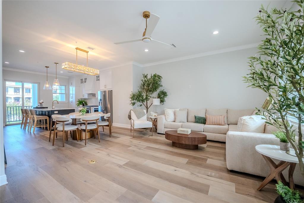 An open-concept living and dining area features light wood floors, a modern kitchen, and furniture — 141 SE WATULA AVENUE, OCALA, FL
