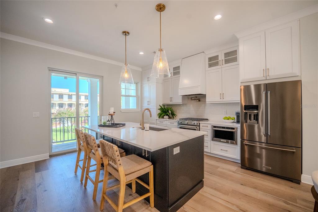 A modern kitchen features a dark island, white cabinetry, stainless steel appliances, and a sliding door — 141 SE WATULA AVENUE, OCALA, FL