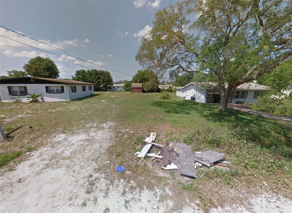 A vacant grassy lot sits between two single-story houses with a pile of debris nearby — 213 PINE AVENUE, EDGEWATER, FL