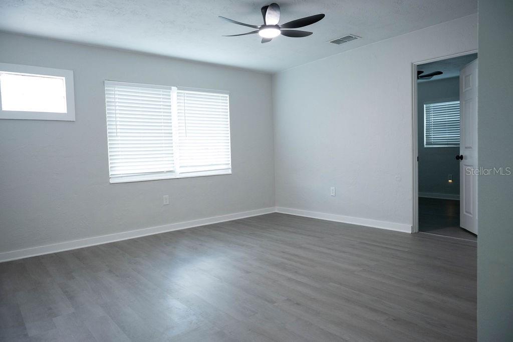 A bedroom with light gray walls, gray wood-look flooring, and a ceiling fan — 5480 70TH LANE N, ST PETERSBURG, FL