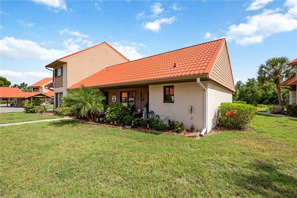 A side view of a tan, two-story townhouse with a red tile roof and landscaping — 6507 DRAW LANE UNIT 68, SARASOTA, FL