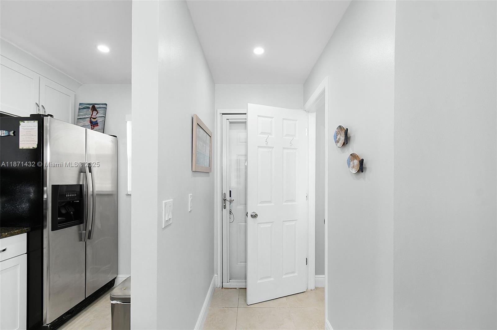 A hallway leads to an open white door next to a stainless steel refrigerator — 9421 S Ocean Dr # 90, Jensen Beach FL 34957, JENSEN BEACH, FL