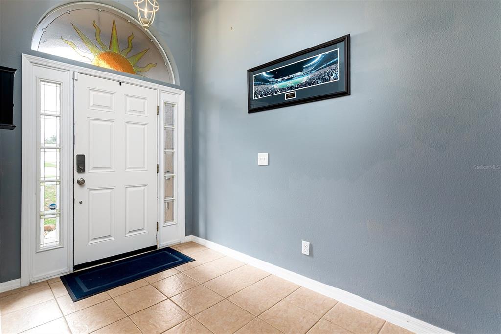 An entryway features a white front door, a sun-themed transom window, and blue walls — 1059 BLUEGRASS DRIVE, GROVELAND, FL