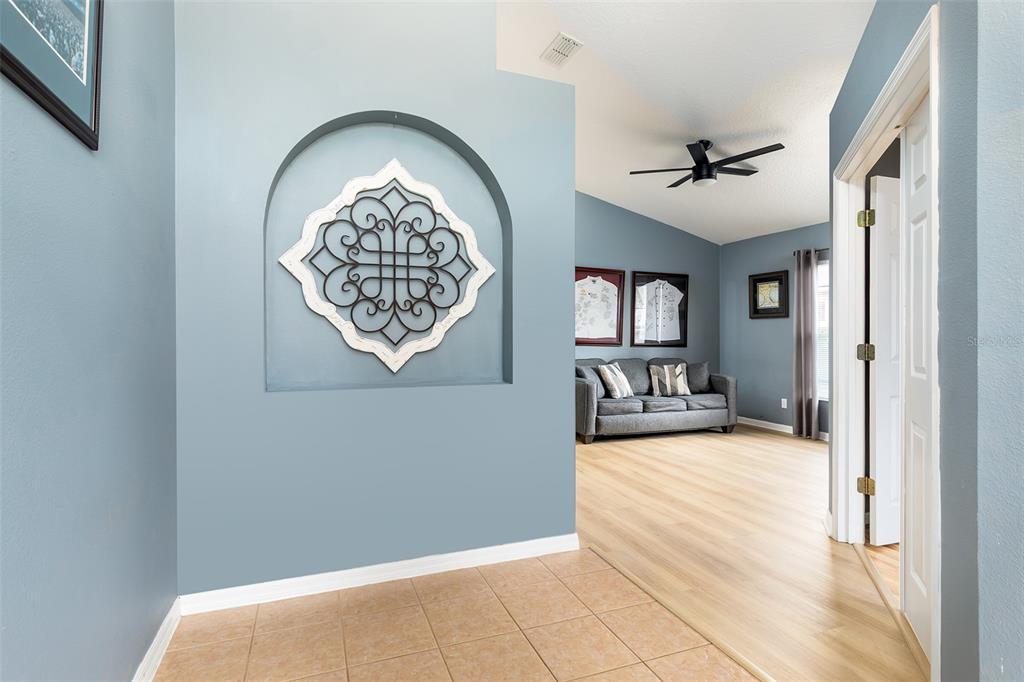 A tiled entryway leads into a living room with light wood flooring and blue walls — 1059 BLUEGRASS DRIVE, GROVELAND, FL