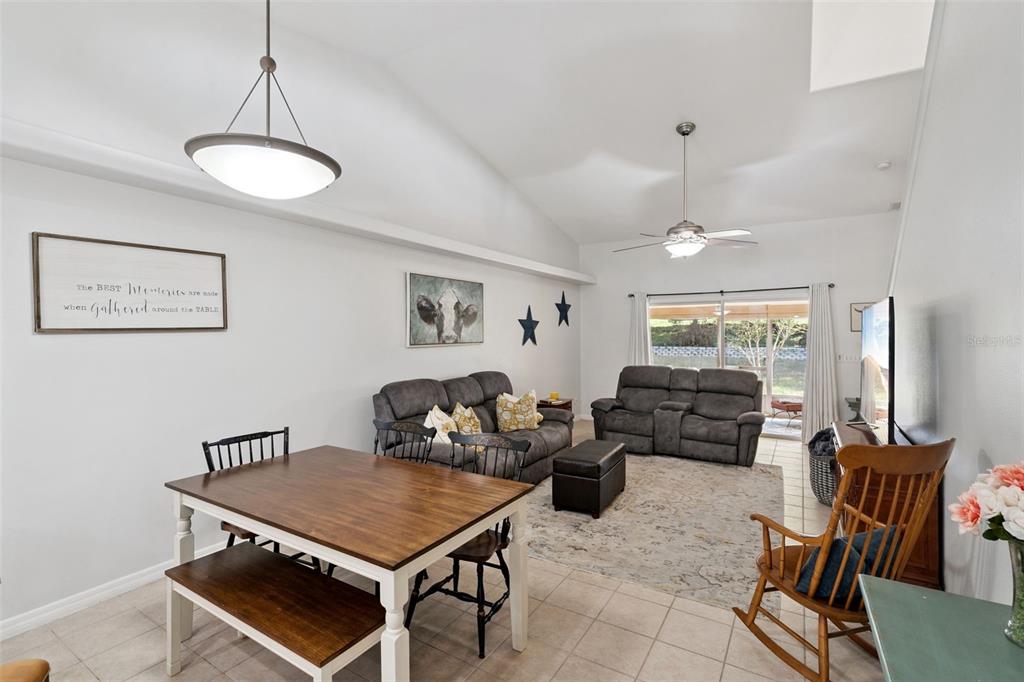 An open-concept living and dining area features vaulted ceilings, tile flooring, and neutral walls — 8856 COURTYARD LANE, GROVELAND, FL