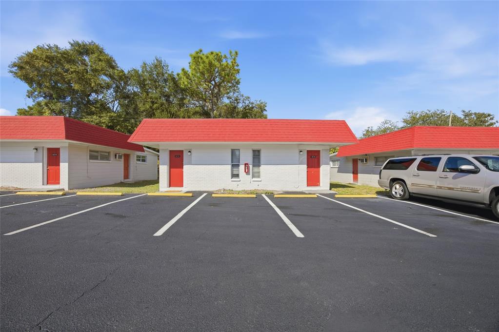 A single-story motel building with white brick walls, red doors, and a red shingled roof — 1302 MORRIS PARK, TAMPA, FL