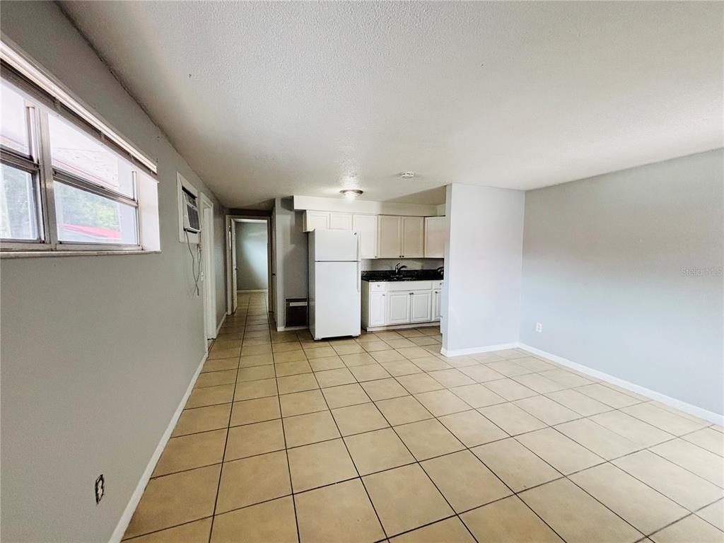 An open-concept kitchen and living area with white cabinets, a white refrigerator, and tiled floors — 1302 MORRIS PARK, TAMPA, FL