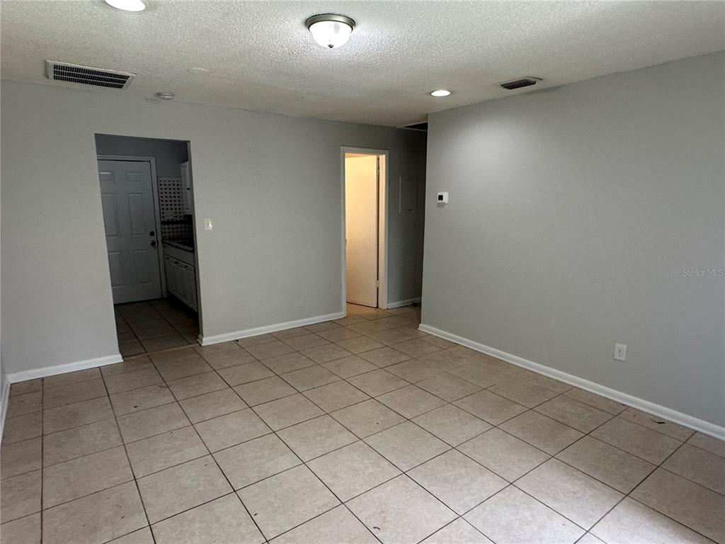 An interior view of a room with light gray walls, beige tile flooring, and two doorways — 8215 N KLONDYKE STREET, TAMPA, FL