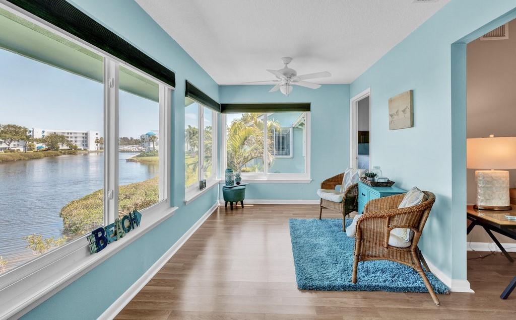 A sunroom with light blue walls, wicker chairs, a blue rug, and large waterfront windows — 6408 S River Run Drive, Sebastian FL 32958, SEBASTIAN, FL
