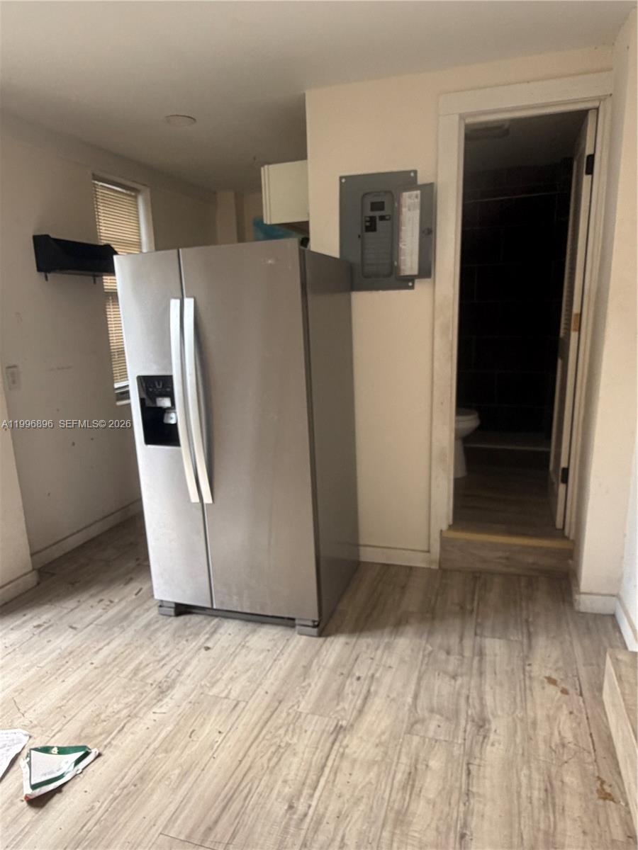 A stainless steel refrigerator stands in a room with light wood-look flooring and a bathroom — 634 SW 10th Ave, Miami FL 33130, MIAMI, FL