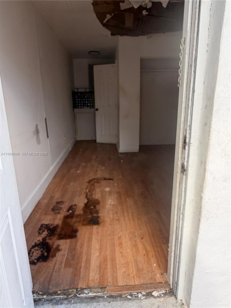 A narrow room features wood-look flooring with significant water damage and a damaged ceiling — 634 SW 10th Ave, Miami FL 33130, MIAMI, FL