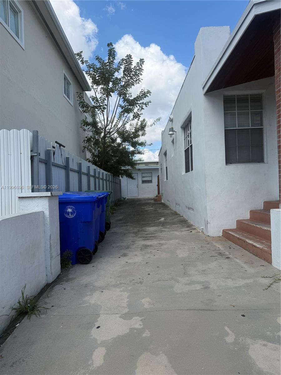 A concrete driveway leads between two white buildings toward a small detached structure — 634 SW 10th Ave, Miami FL 33130, MIAMI, FL