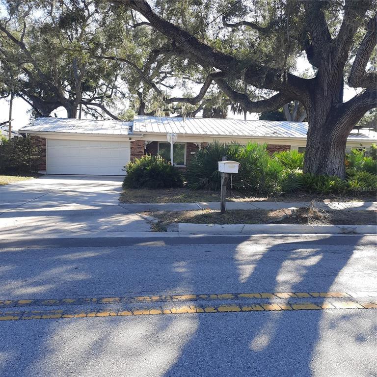 A single-story brick house with a white metal roof and a large oak tree — 4806 W SAN JOSE STREET, TAMPA, FL