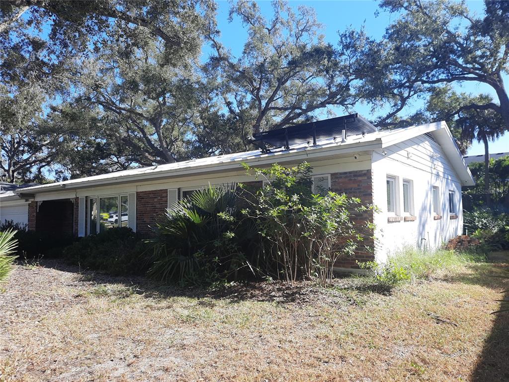 A single-story brick and white siding house features a solar panel array on the roof — 4806 W SAN JOSE STREET, TAMPA, FL