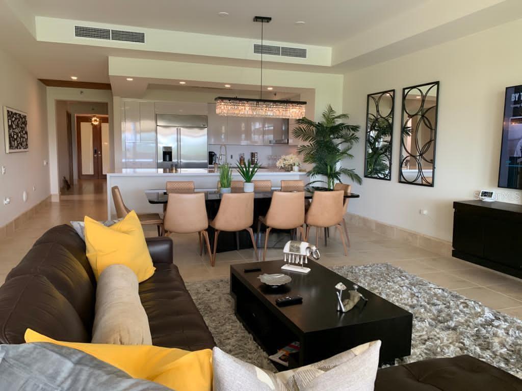 An open-concept living and dining area features a dark leather sofa, kitchen, and dining table — 500 PLANTATION DR. UNIT 304, DORADO, PR