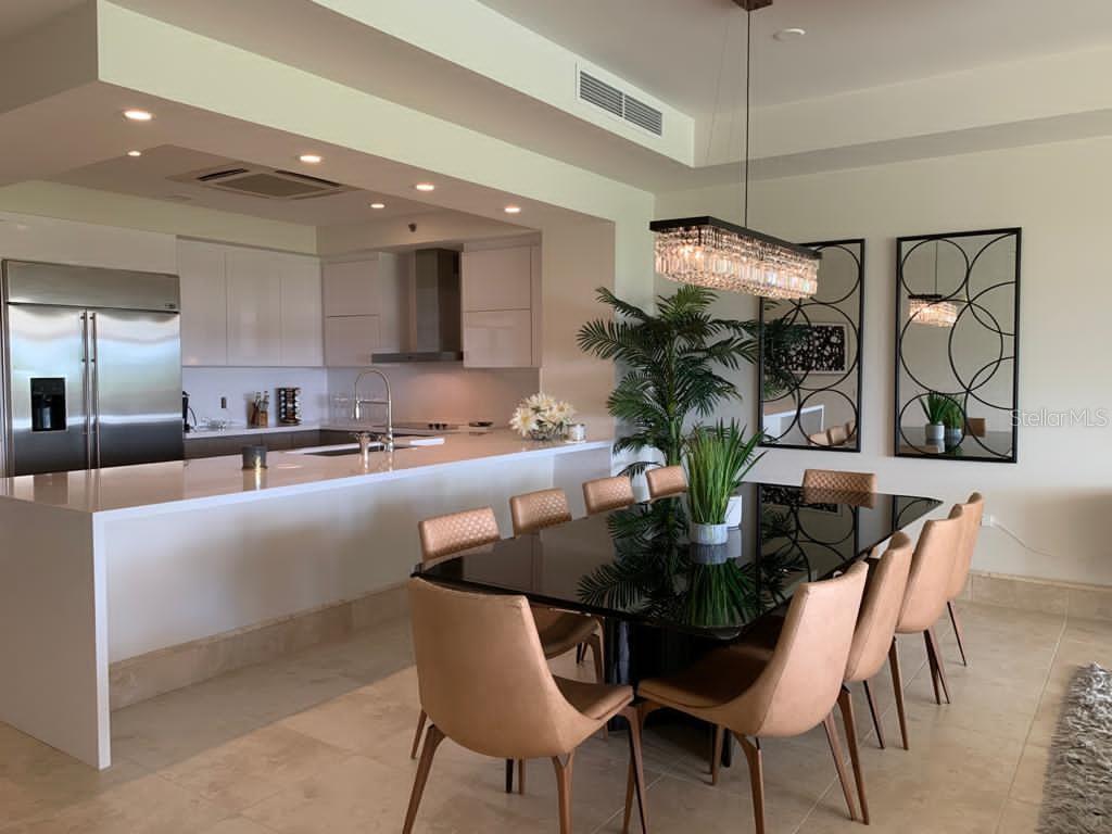 A modern kitchen with white cabinetry and a dining area featuring a black table — 500 PLANTATION DR. UNIT 304, DORADO, PR