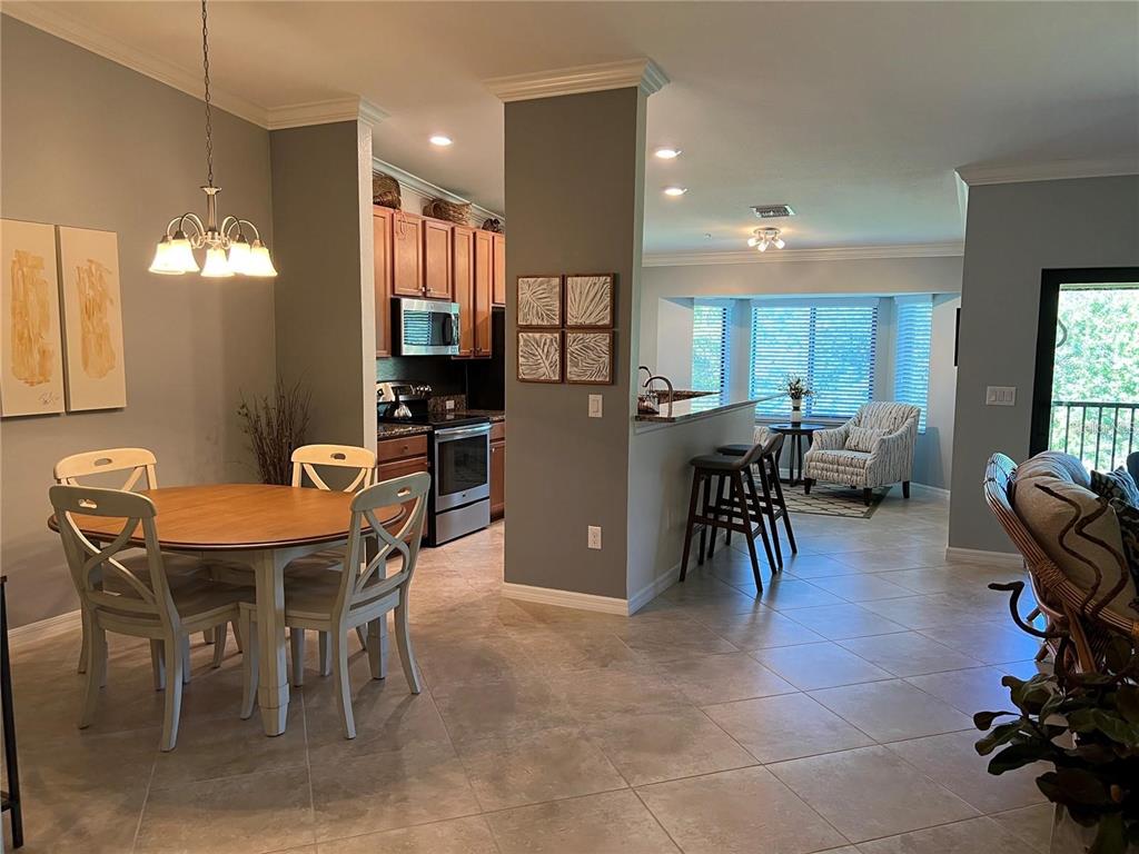 An open-concept dining area and kitchen with tile flooring and a breakfast bar — 6611 GRAND ESTUARY TRAIL UNIT 204, BRADENTON, FL