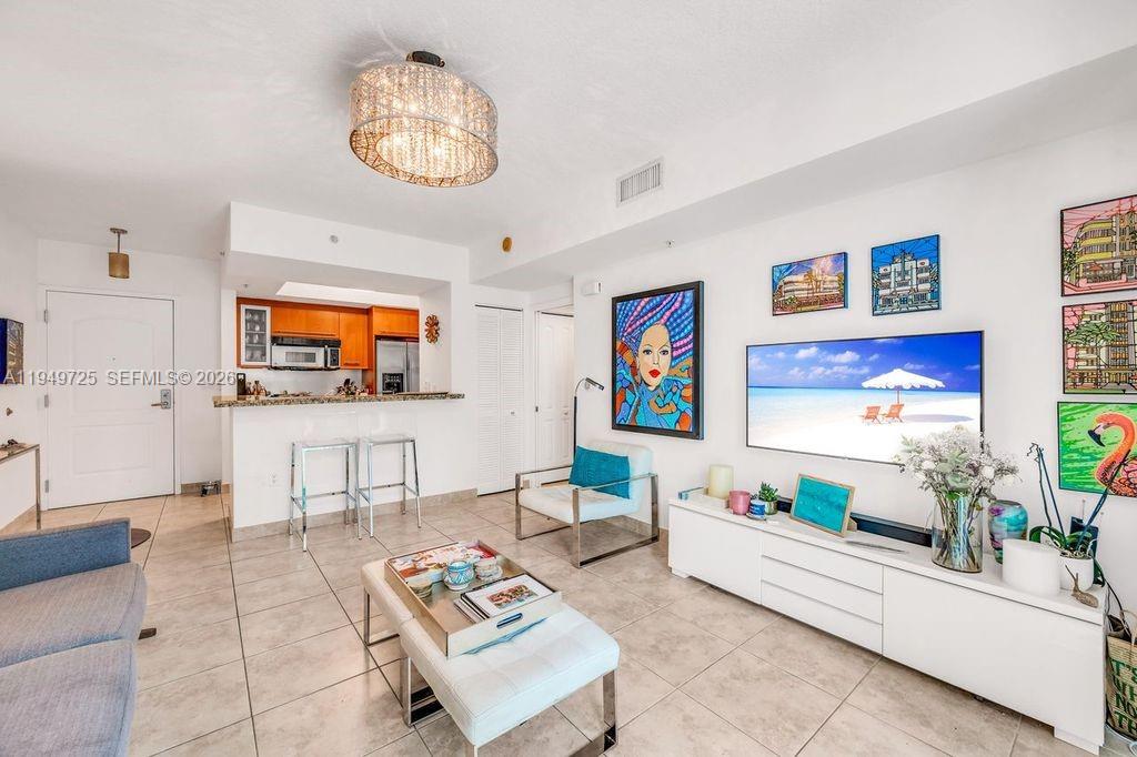 A living room features white tile floors, a modern white media console, and colorful wall art — 110 Washington Ave # 2310, Miami Beach FL 33139, MIAMI BEACH, FL