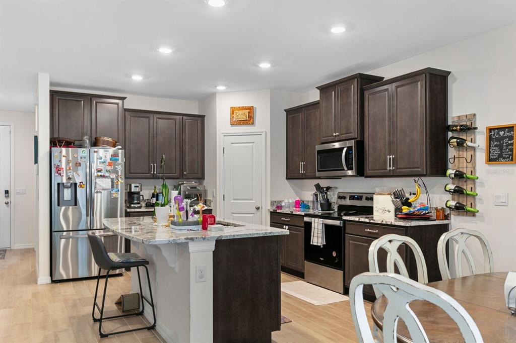 A kitchen features dark wood cabinets, granite countertops, a center island, and stainless steel appliances — 1454 NW 136TH BOULEVARD, NEWBERRY, FL