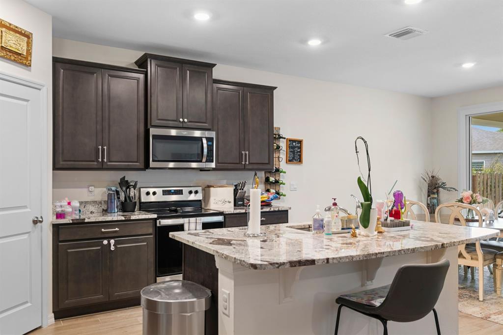 A kitchen features dark wood cabinets, granite countertops, a center island, and stainless steel appliances — 1454 NW 136TH BOULEVARD, NEWBERRY, FL