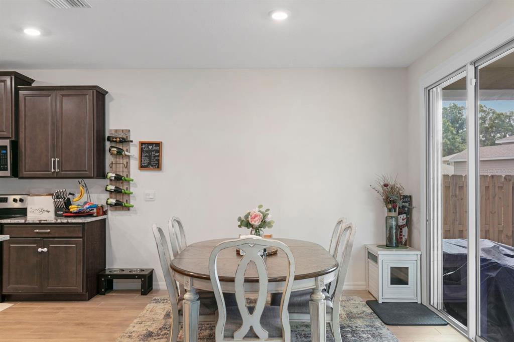 A dining area features a round wooden table, four chairs, and dark wood kitchen cabinets — 1454 NW 136TH BOULEVARD, NEWBERRY, FL