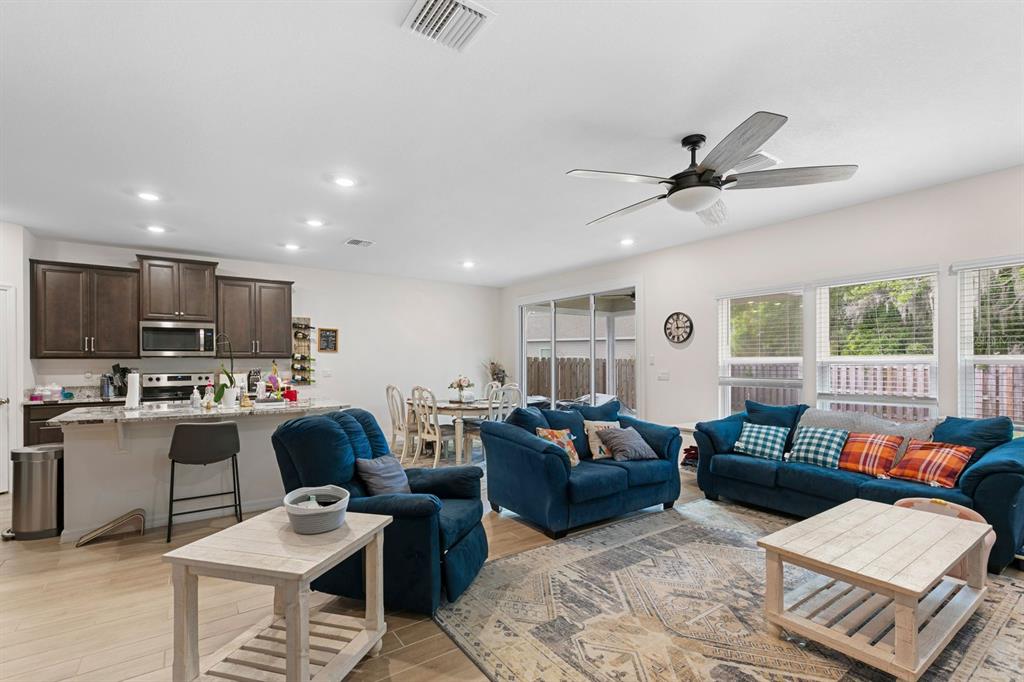 An open-concept living room and kitchen featuring dark wood cabinets, blue furniture, and tile flooring — 1454 NW 136TH BOULEVARD, NEWBERRY, FL