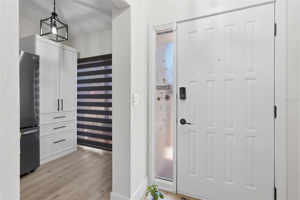 An entryway features a white door with a sidelight, wood-look flooring, and white cabinetry — 3649 WASH ROAD UNIT B, LAKE WORTH, FL