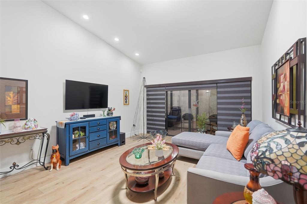A living room features a blue media console, a grey sectional sofa, and sliding glass doors — 3649 WASH ROAD UNIT B, LAKE WORTH, FL