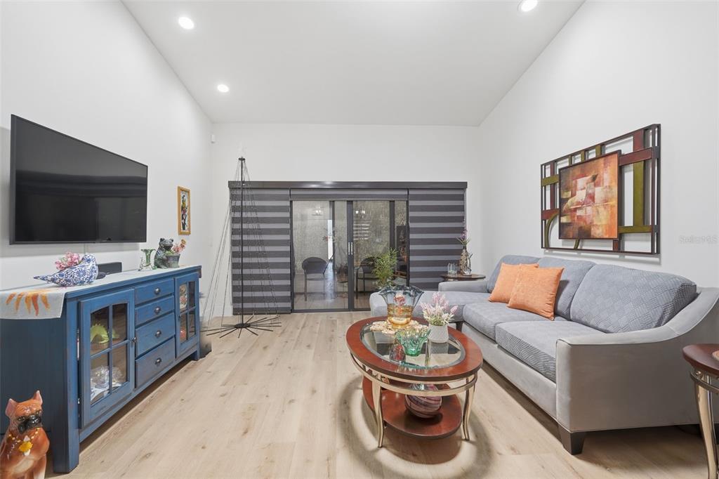 A living room features a blue media console, a gray sectional sofa, and sliding glass doors — 3649 WASH ROAD UNIT B, LAKE WORTH, FL