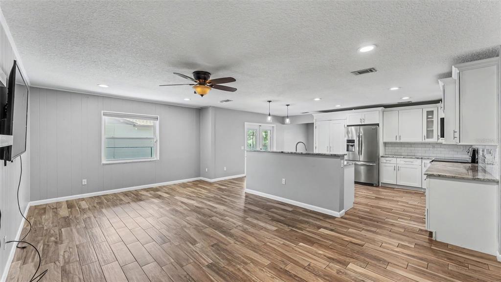 An open-concept living room and kitchen with wood-look tile flooring and white cabinetry — 1717 TIERRA ALTA DRIVE, LAKELAND, FL