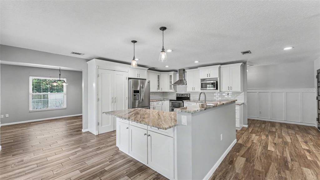 A kitchen with white cabinets, a granite-topped island, and wood-look flooring — 1717 TIERRA ALTA DRIVE, LAKELAND, FL