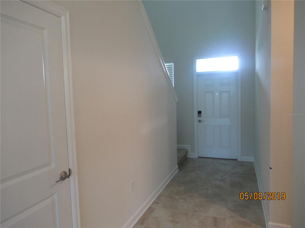An entryway features tile flooring, a white door with a transom window, and a staircase — 4606 RHYTHM ROAD, KISSIMMEE, FL