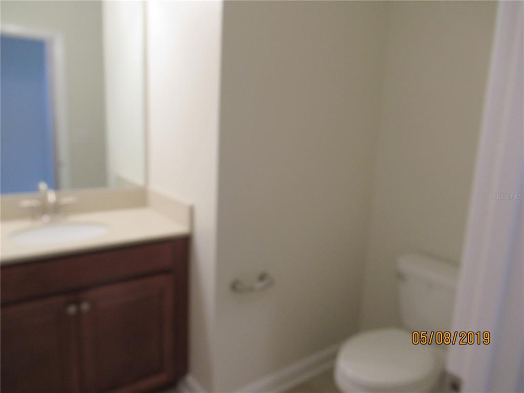 A bathroom features a wooden vanity with a sink, a mirror, and a toilet — 4606 RHYTHM ROAD, KISSIMMEE, FL