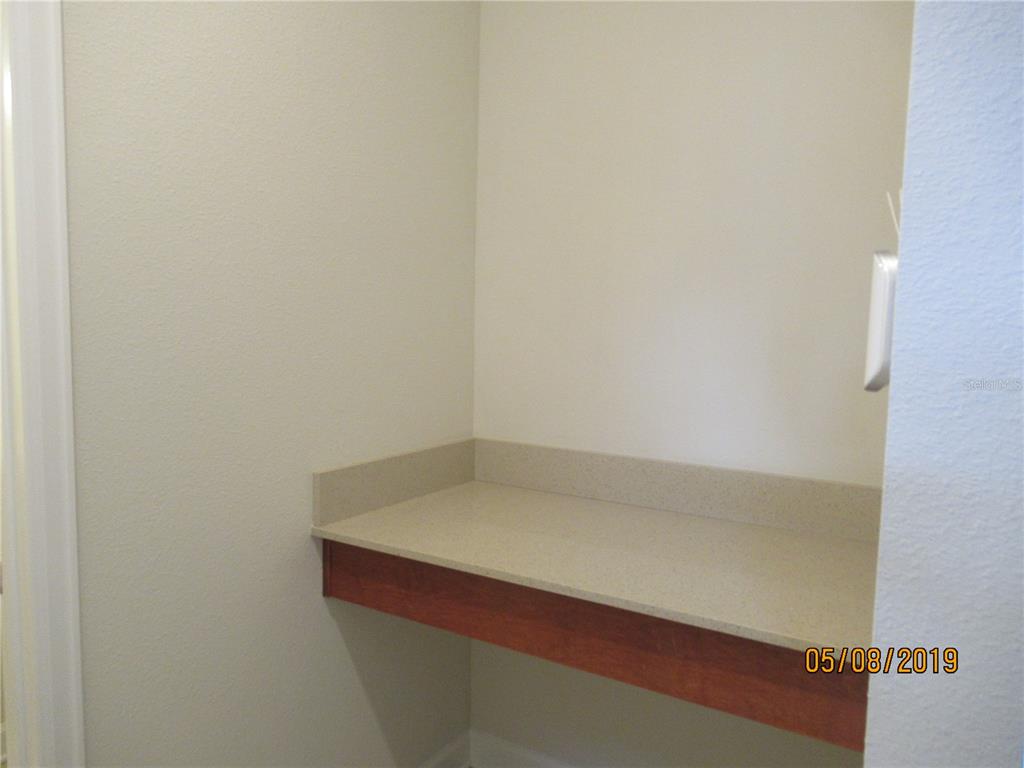 A built-in desk with a light-colored countertop and wooden trim against a plain wall — 4606 RHYTHM ROAD, KISSIMMEE, FL