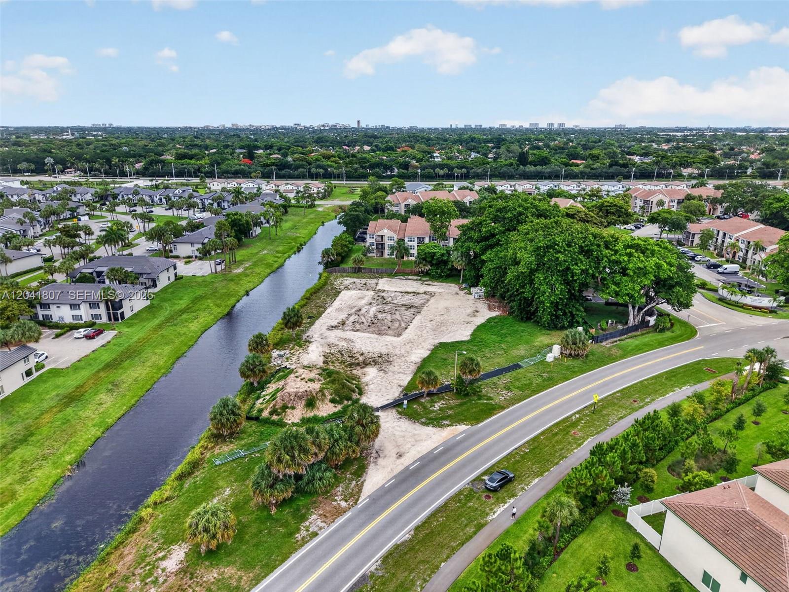 An aerial view shows a vacant, cleared lot situated between a canal and a road — 22962 Camino Del Mar, Boca Raton FL 33433, BOCA RATON, FL