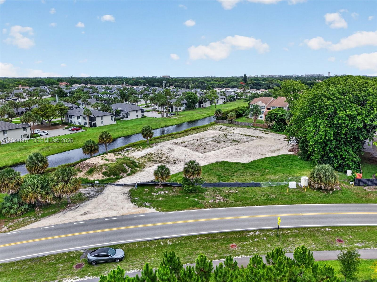 An aerial view shows a vacant, cleared lot next to a canal and residential buildings — 22962 Camino Del Mar, Boca Raton FL 33433, BOCA RATON, FL