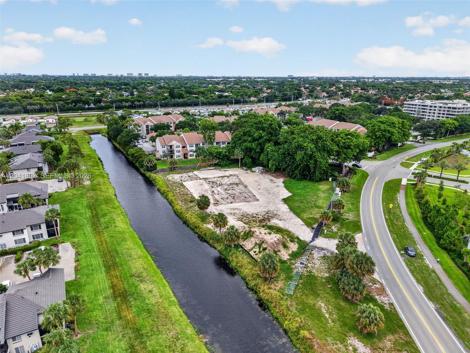 An aerial view shows a vacant lot situated between a canal and a curved road — 22962 Camino Del Mar, Boca Raton FL 33433, BOCA RATON, FL