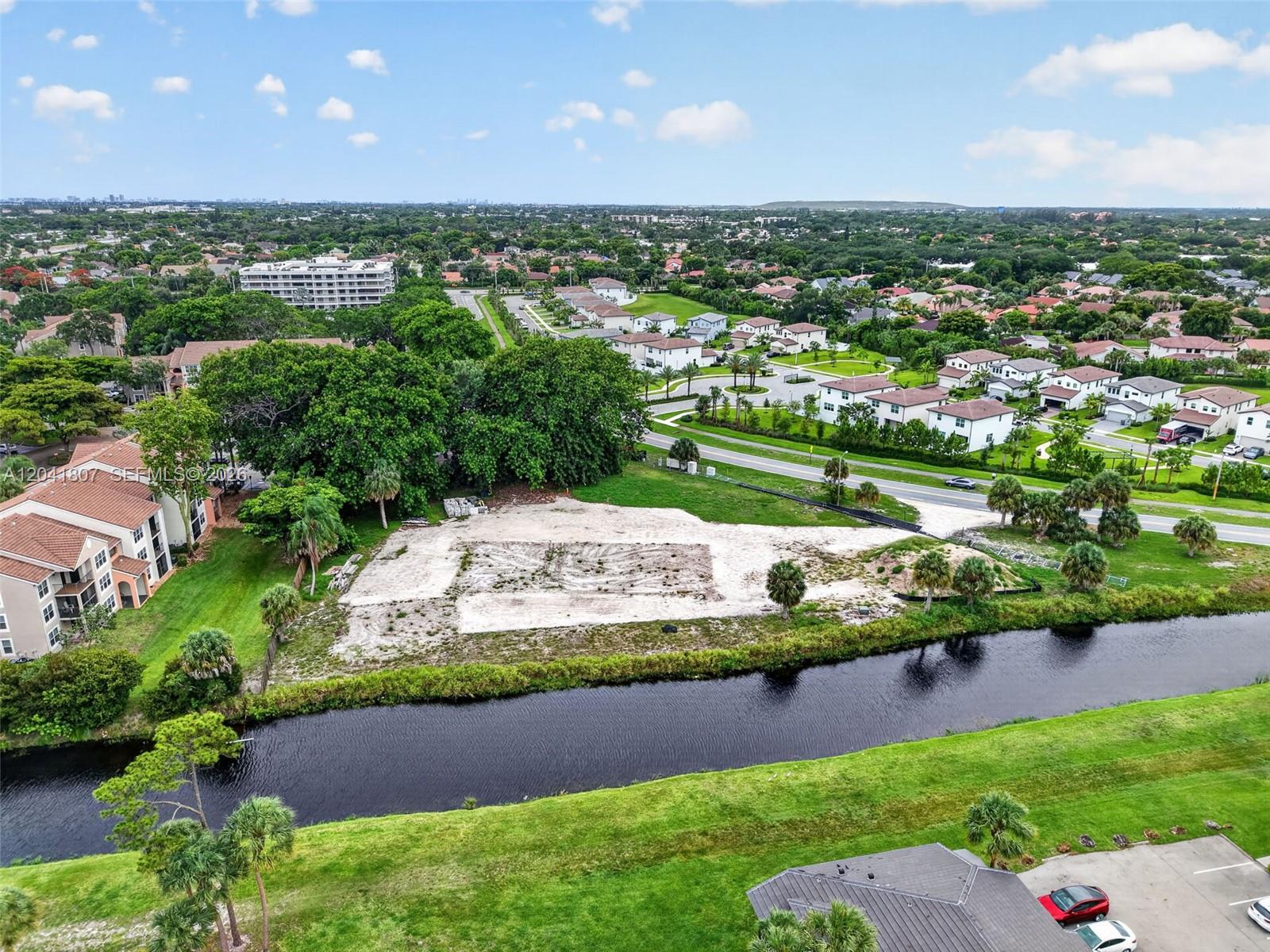An aerial view shows a cleared vacant lot situated between a canal and a road — 22962 Camino Del Mar, Boca Raton FL 33433, BOCA RATON, FL