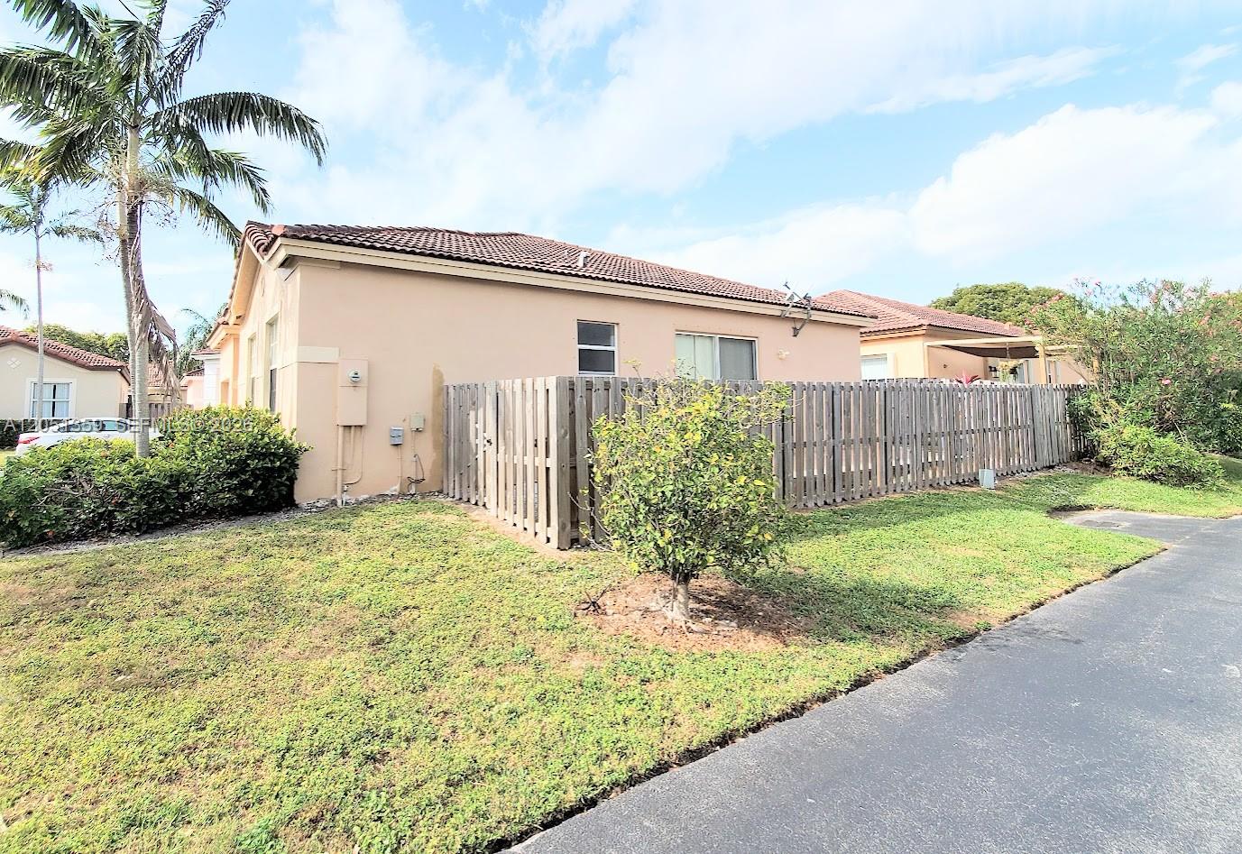 A beige house with a wooden fence and a palm tree in the front yard — 21460 SW 90th Ct, Cutler Bay FL 33189, CUTLER BAY, FL