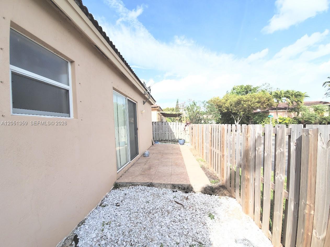 A side yard features a tiled patio, white gravel ground cover, and a wooden fence — 21460 SW 90th Ct, Cutler Bay FL 33189, CUTLER BAY, FL
