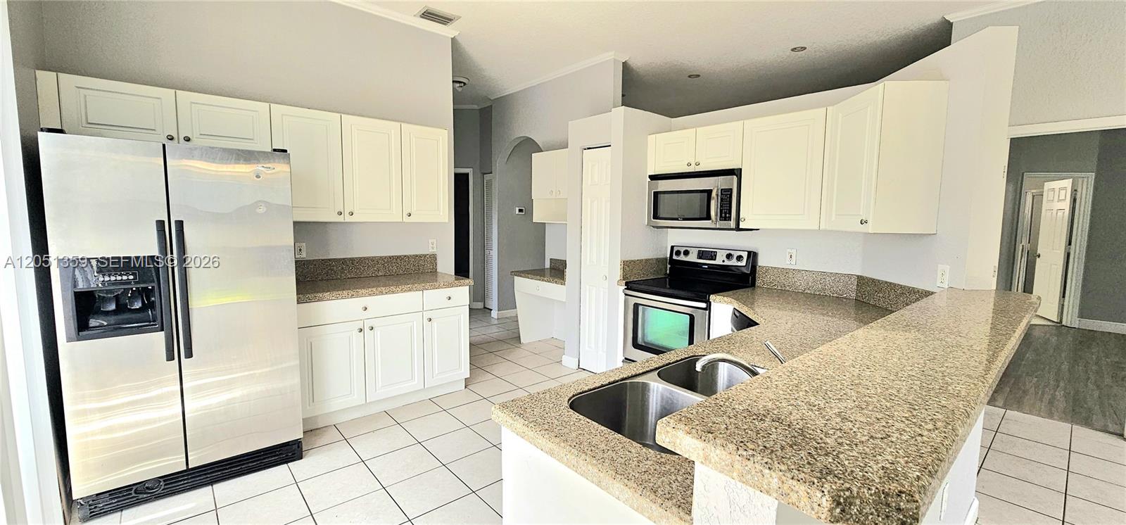 A kitchen features white cabinets, granite countertops, stainless steel appliances, and light-colored tile flooring — 21460 SW 90th Ct, Cutler Bay FL 33189, CUTLER BAY, FL
