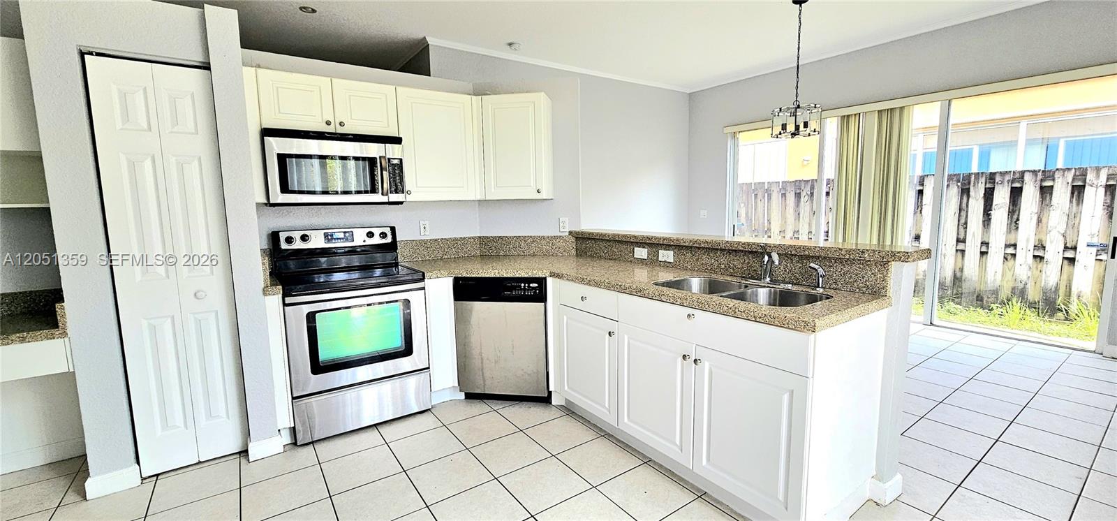 A kitchen features white cabinets, stainless steel appliances, granite countertops, and tile flooring — 21460 SW 90th Ct, Cutler Bay FL 33189, CUTLER BAY, FL