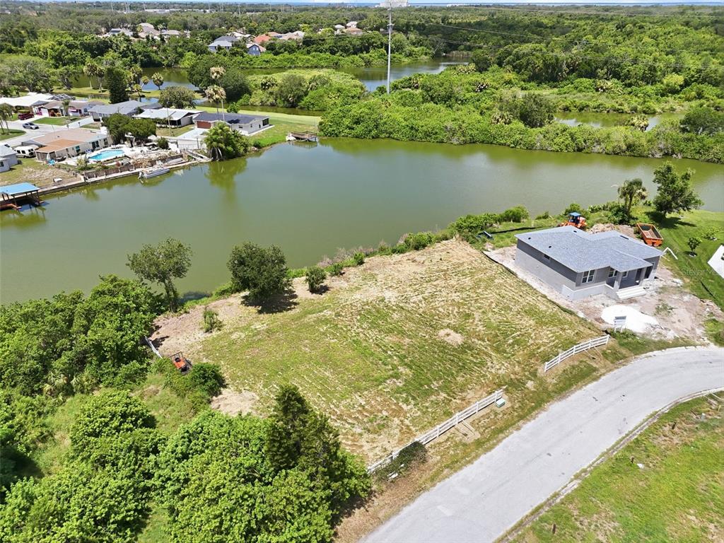 An aerial view shows a vacant waterfront lot next to a newly constructed house — 1503 JACKSON DRIVE, HOLIDAY, FL