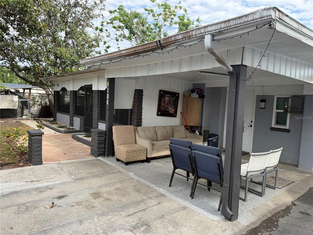 A covered patio area features a beige sofa, several chairs, and a concrete floor — 4106 W SOUTH AVENUE, TAMPA, FL