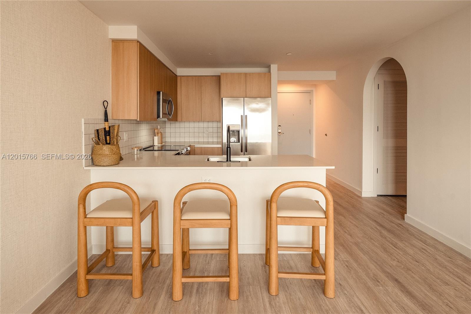 A kitchen features light wood cabinets, white countertops, three wooden bar stools, and an arched doorway — 275 SW 6th St # 5303, Miami FL 33130, MIAMI, FL