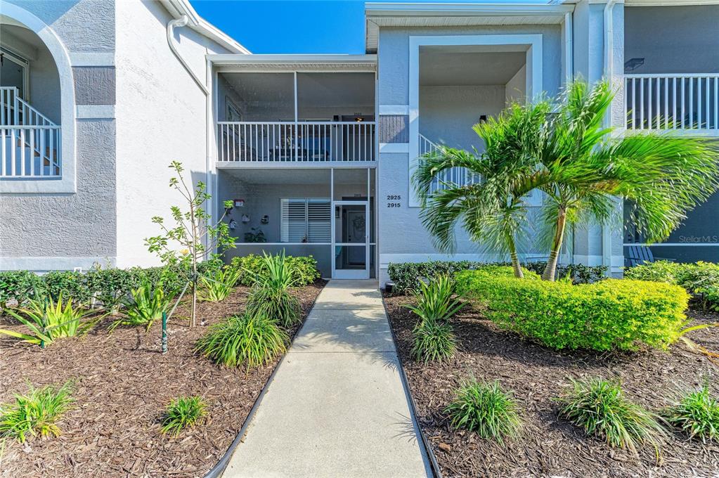 A concrete walkway leads to the screened-in entrance of a two-story residential building — 4639 CHAPEL HILL DRIVE UNIT 2925, SARASOTA, FL